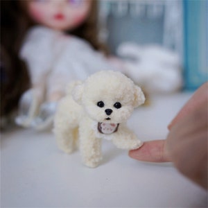 May include: A small, white, fluffy toy dog with black eyes and a brown paw print on its chest. The dog is standing on a white surface and is looking at the camera.