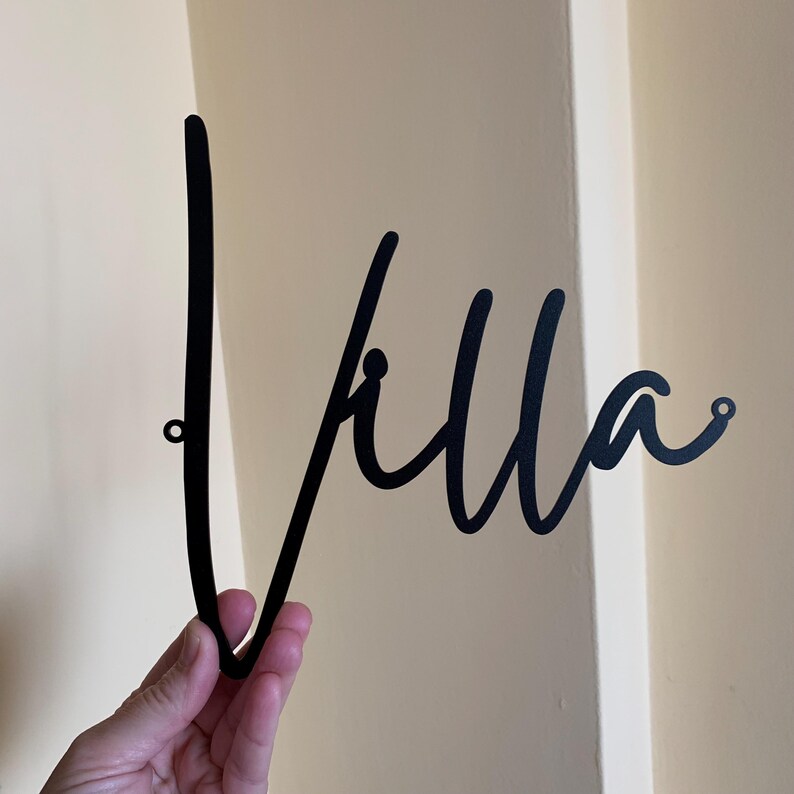 May include: Black metal wall decor with the word "Villa" written in a cursive script.