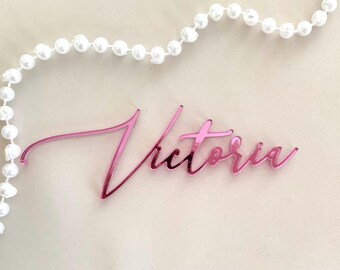 Peut inclure: Plaque de nom en acrylique rose avec le nom "Victoria" écrit en cursive.
