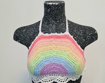 Puede incluir: Un top halter de crochet arcoíris con un ribete de crochet blanco. El top está hecho de un hilo suave y ligero y presenta un diseño de arcoíris.