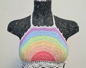 Puede incluir: Un top halter de crochet arcoíris con un ribete de crochet blanco. El top está hecho de un hilo suave y ligero y presenta un diseño de arcoíris con un centro rosa.