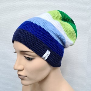 May include: A blue, green, white, and light blue striped crocheted beanie with a small white label that says "Dmmd".