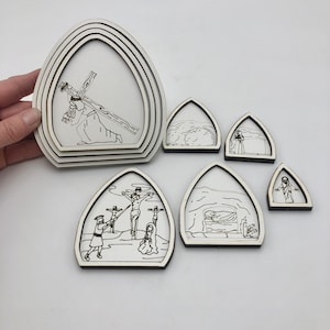 May include: Set of 8 wooden laser cut out shapes depicting scenes from the Stations of the Cross. The shapes are white and feature black line drawings of Jesus carrying the cross, Jesus being crucified, and Jesus in the tomb.