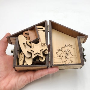 May include: A wooden box with a hinged lid, open to reveal a nativity scene with a star, animals, and a manger. The box is made of light brown wood and has a dark brown stain.