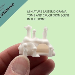 May include: White 3D printed miniature Easter diorama with a tomb and crucifixion scene in the front. The diorama is held in a hand.