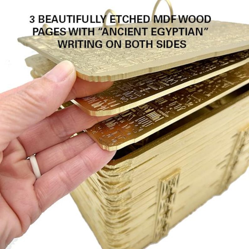May include: A stack of three gold-coloured MDF wood pages with "Ancient Egyptian" writing etched on both sides. The pages are stacked on top of each other and are being held by a hand.
