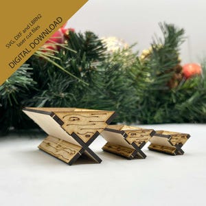 May include: Three wooden mangers of varying sizes, with a wood grain pattern and a slightly distressed finish. The mangers are arranged in a row from largest to smallest, with the largest manger in the foreground. The mangers are made of wood and have a natural brown colour.