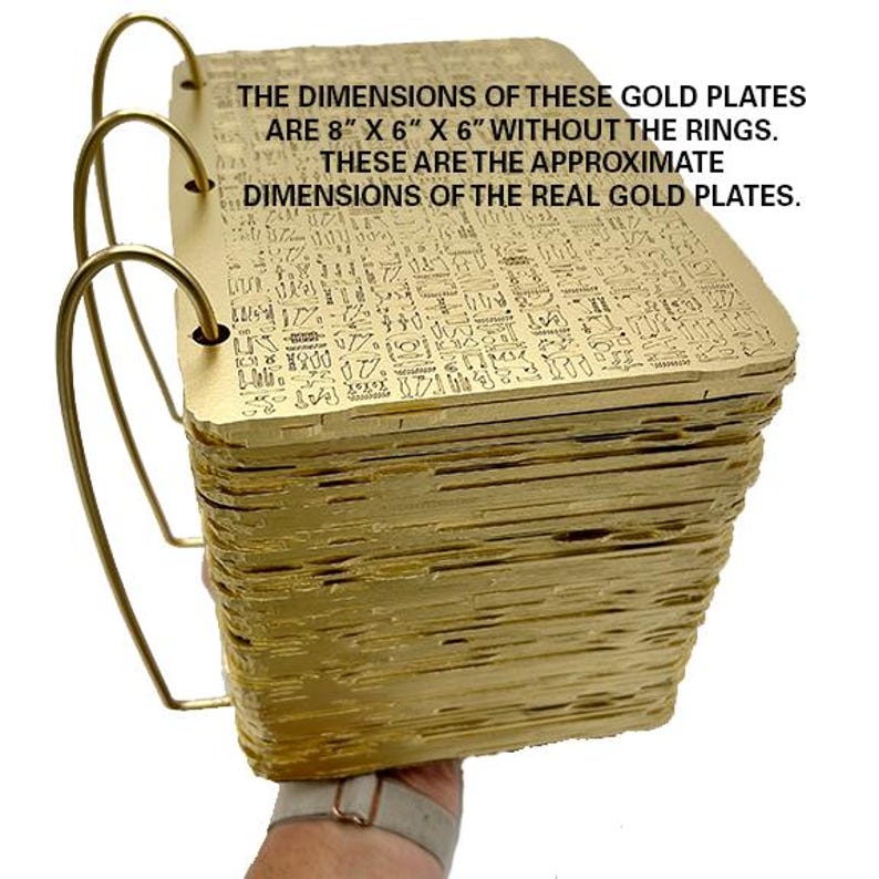 May include: A stack of gold-coloured plates with intricate designs, held by a hand. The plates are approximately 8 inches by 6 inches by 6 inches, excluding the rings. "THE DIMENSIONS OF THESE GOLD PLATES ARE 8" X 6" X 6" WITHOUT THE RINGS. THESE ARE THE APPROXIMATE DIMENSIONS OF THE REAL GOLD PLATES."