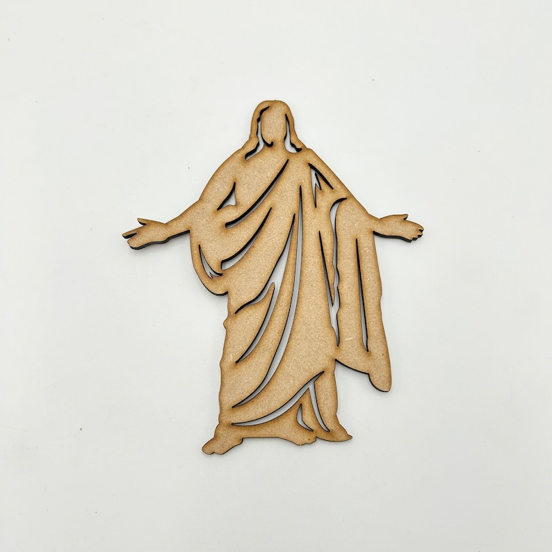 May include: A wooden cutout of a person in a robe with their arms outstretched. The cutout is a light brown color and has a simple design.