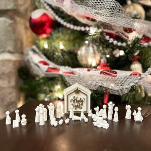 May include: White nativity scene set with a wooden stable that says "Holy Night" in gold lettering. The set includes figures of Mary, Joseph, baby Jesus, angels, shepherds, and animals.