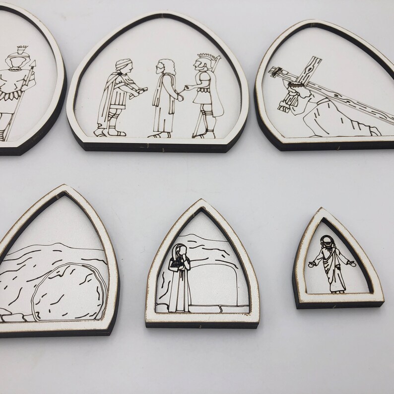 May include: Set of six white wooden arches with black line drawings depicting scenes from the Passion of Christ. The scenes include Jesus carrying the cross, Jesus being nailed to the cross, Jesus being taken down from the cross, Jesus being buried, and Jesus rising from the tomb.