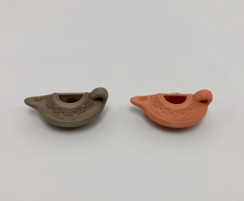 Puede incluir: Dos peque&ntilde;as l&aacute;mparas de aceite de cer&aacute;mica, una es marr&oacute;n y la otra naranja. Ambas l&aacute;mparas tienen un dise&ntilde;o decorativo alrededor del borde.