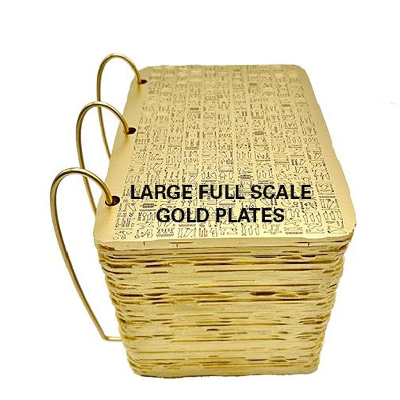 May include: A large, gold-coloured book with a black inscription on the cover that reads "LARGE FULL SCALE GOLD PLATES". The book is bound with three metal rings and appears to be made of many thin, layered sheets.