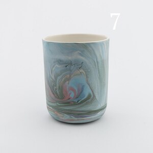 May include: A blue and green ceramic mug with a marbled pattern. The mug has a white rim and a light blue interior.