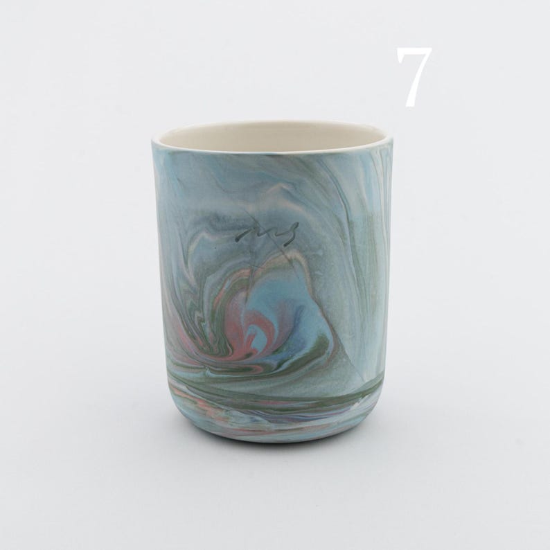 May include: A blue and green ceramic mug with a marbled pattern. The mug has a white rim and a light blue interior.