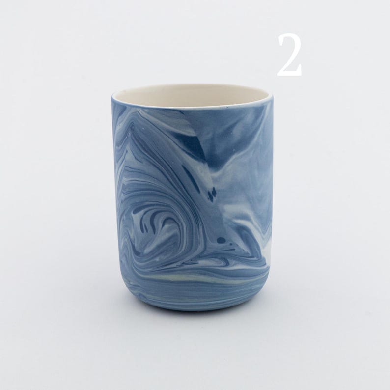 May include: A blue and white marbled ceramic mug. The mug has a swirling pattern of blue and white.