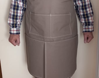 May include: A brown canvas apron with white stitching and multiple pockets. The apron has adjustable straps and a large pocket on the front.