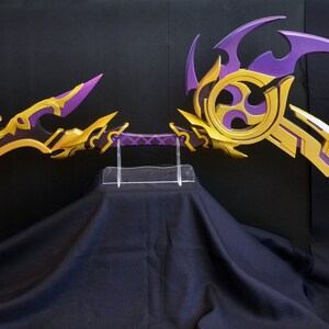 May include: A pair of purple and gold fantasy-style bows with intricate designs. The bows are displayed on a clear acrylic stand.