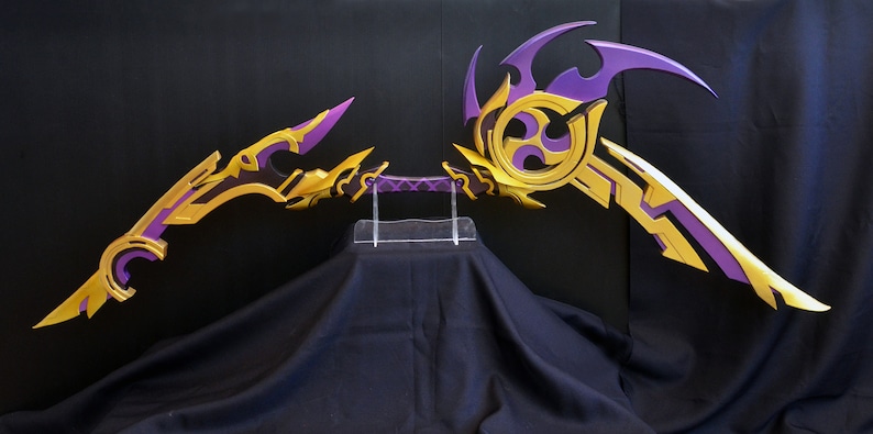 May include: A pair of purple and gold fantasy-style bows with intricate designs. The bows are displayed on a clear acrylic stand.
