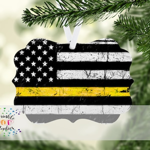 May include: A distressed American flag ornament with a thin yellow stripe across the middle. The ornament is made of metal and has a white ribbon for hanging.