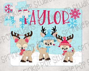 May include: A blue and white jigsaw puzzle with a winter theme. The puzzle features three reindeer wearing hats and scarves. The name "Taylor" is written in red letters at the top of the puzzle.