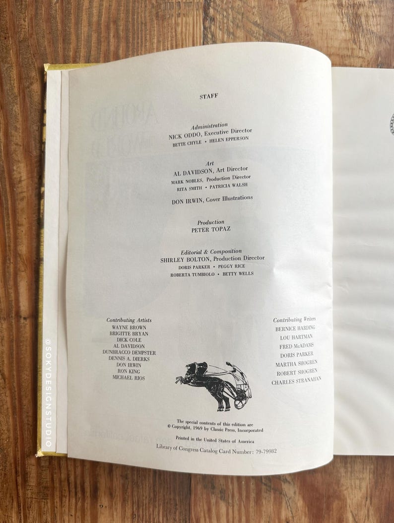 Peut inclure: Page d'un livre ouvert avec du texte listant le personnel, l'art et les cr&eacute;dits de production. La page est tir&eacute;e d'une publication de 1969, avec une petite illustration d'une figure avec une arbal&egrave;te. Le livre est ouvert sur une surface en bois.