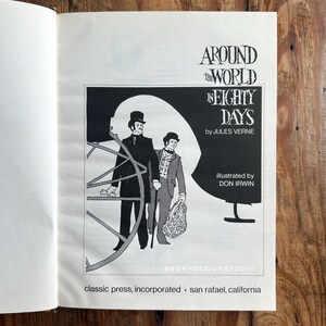 Peut inclure: Livre ouvert avec une illustration en noir et blanc de "Le Tour du monde en quatre-vingts jours" de Jules Verne. L'image montre deux hommes en costume d'&eacute;poque, avec le nom de l'auteur et de l'illustrateur.