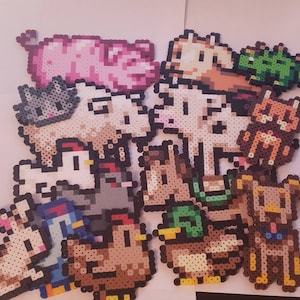 May include: A collection of pixel art farm animals, including a pink pig, a gray cat, a white cow, a brown dog, a duck, a chicken, and a rabbit. The animals are made from colorful plastic beads.