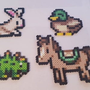 May include: Four pixel art animal designs: a rabbit with pink ears, a duck with a green head, a green creature, and a brown horse with a saddle. Each design is made of small, colorful beads.