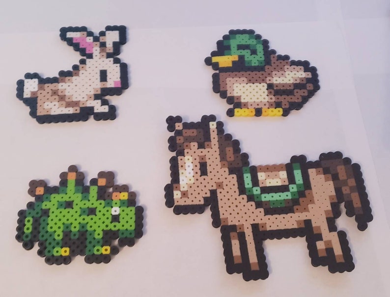 May include: Four pixel art animal designs: a rabbit with pink ears, a duck with a green head, a green creature, and a brown horse with a saddle. Each design is made of small, colorful beads.