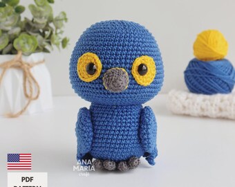 Puede incluir: Un búho azul tejido a mano con detalles amarillos en los ojos y un pico gris. El búho está de pie. La imagen también muestra una bola de hilo azul, una bola de hilo amarillo y una superficie blanca. El texto "PDF PATTERN ENGLISH" es visible.