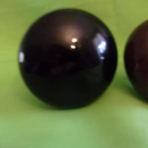 May include: Two smooth, round ornaments. One is black and the other is a dark brown color.