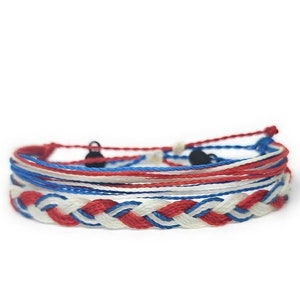May include: A braided bracelet with red, white, and blue threads. The bracelet is made of multiple strands of string and has a braided design.