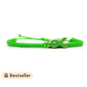 May include: A green awareness ribbon charm bracelet. The bracelet is made of green cord and features a green ribbon charm with a gold outline.