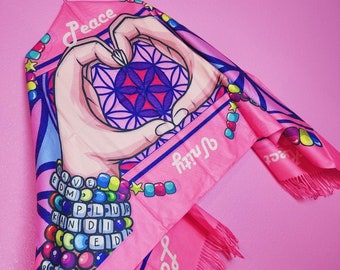 May include: Pink fringed scarf with a heart-shaped design and the words "Peace", "Love", and "Unity" in a colorful font. The scarf has a beaded border with colorful letters.