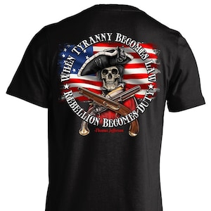 May include: Black t-shirt featuring a graphic of a skull wearing a tricorn hat and holding crossed pistols. The graphic is surrounded by an American flag and the text "When Tyranny Becomes Law Rebellion Becomes Duty -Thomas Jefferson".