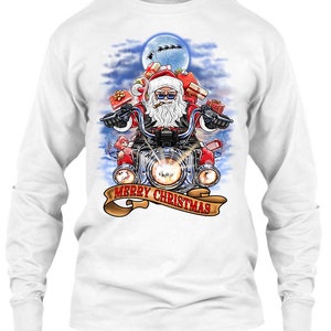 May include: White long-sleeve shirt featuring a graphic of Santa Claus riding a motorcycle, carrying gifts, and smoking a cigar. The design includes a banner that reads "MERRY CHRISTMAS" and a full moon in the background.
