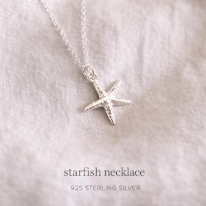 May include: A silver starfish necklace on a white background. The necklace features a detailed starfish pendant suspended from a delicate chain. The text "starfish necklace" and "925 STERLING SILVER" are displayed below the necklace.