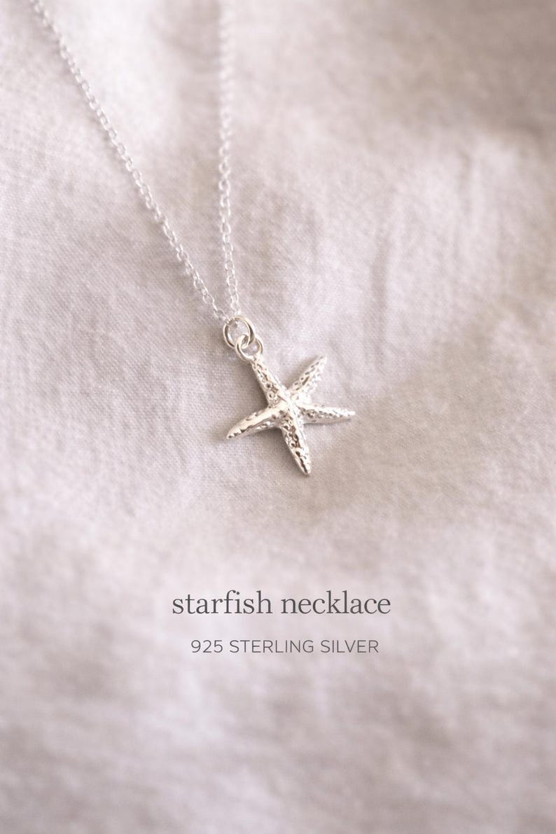 May include: A silver starfish necklace on a white background. The necklace features a detailed starfish pendant suspended from a delicate chain. The text "starfish necklace" and "925 STERLING SILVER" are displayed below the necklace.