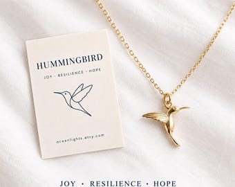 May include: A gold-toned hummingbird pendant on a delicate chain, accompanied by a rectangular card featuring the text HUMMINGBIRD, JOY, RESILIENCE, HOPE, a line-art hummingbird illustration, and the website address oceanlights.etsy.com.