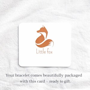 May include: A rectangular white card featuring a stylized orange fox graphic and the text Little fox in orange lettering. Below the card, the text reads: Your bracelet comes beautifully packaged with this card &ndash; ready to gift.