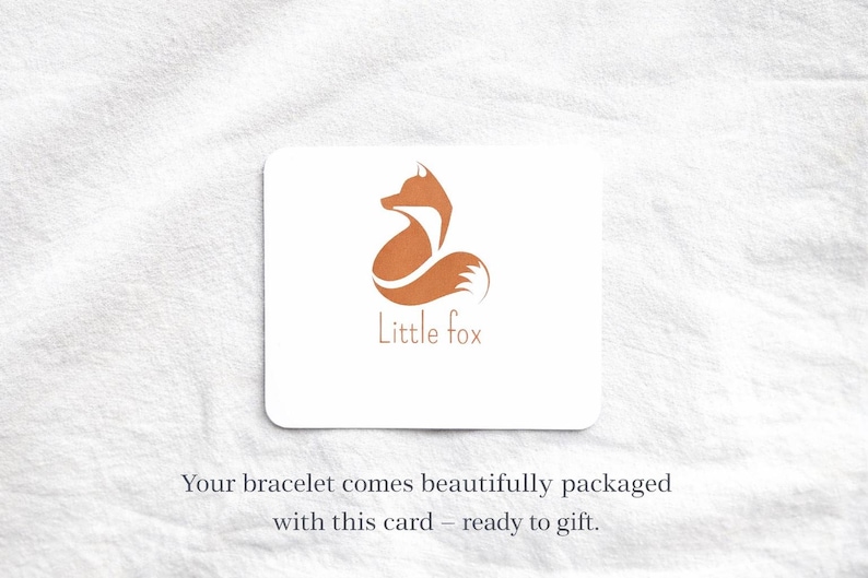 May include: A rectangular white card featuring a stylized orange fox graphic and the text Little fox in orange lettering. Below the card, the text reads: Your bracelet comes beautifully packaged with this card &ndash; ready to gift.