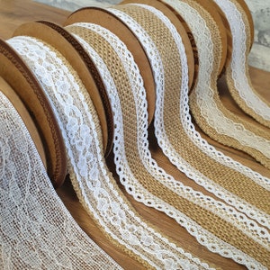 May include: Rolls of burlap ribbon with white lace trim. The ribbon is brown and the lace is white. The ribbon is rolled up on cardboard spools.