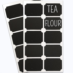 May include: Two sheets of black chalkboard labels with white borders and rounded corners. The labels are blank except for two labels that say "TEA" and "FLOUR" in white text.