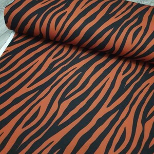 Pu&ograve; includere: Tessuto arancione e nero con motivo a zebre.