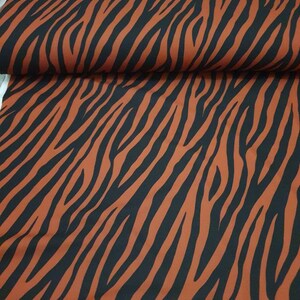 Pu&ograve; includere: Tessuto arancione e nero con motivo a zebre.