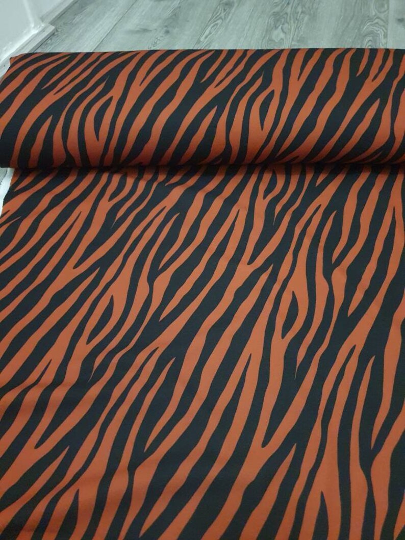 Pu&ograve; includere: Tessuto arancione e nero con motivo a zebre.
