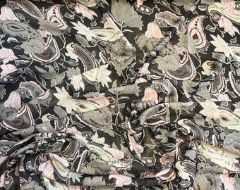 May include: A black fabric with a floral paisley pattern in shades of gray, pink, and white. The fabric is draped, showing the intricate design of leaves and teardrop shapes.