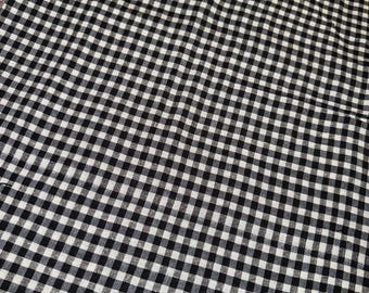 May include: A black and white checkered fabric with a classic gingham pattern. The fabric is tightly woven, creating a grid of small, evenly spaced squares. The pattern is a timeless design, suitable for various sewing and crafting projects.