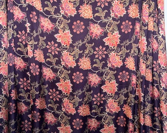May include: A dark purple fabric with a floral pattern in shades of pink, orange, and gold. The fabric has a subtle sheen and a soft texture.